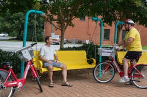 two cyclists chatting at a public bench